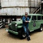 blonde man in front of green truck
